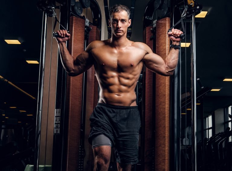 muscular man is doing exercises with training apparatus
